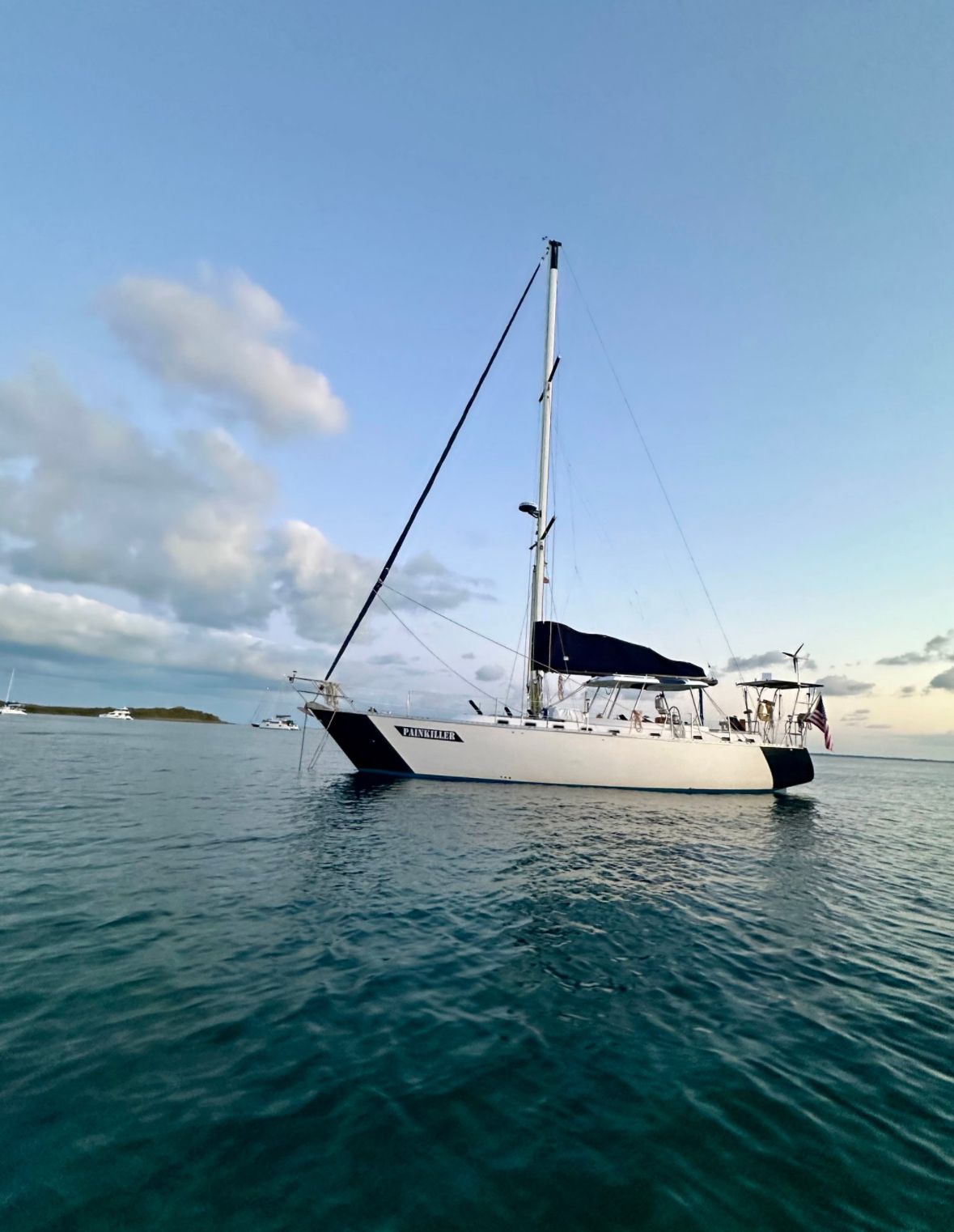 White sailboat on calm turquoise water under a blue sky with light clouds