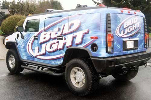 A bud light truck is parked on the side of the road.