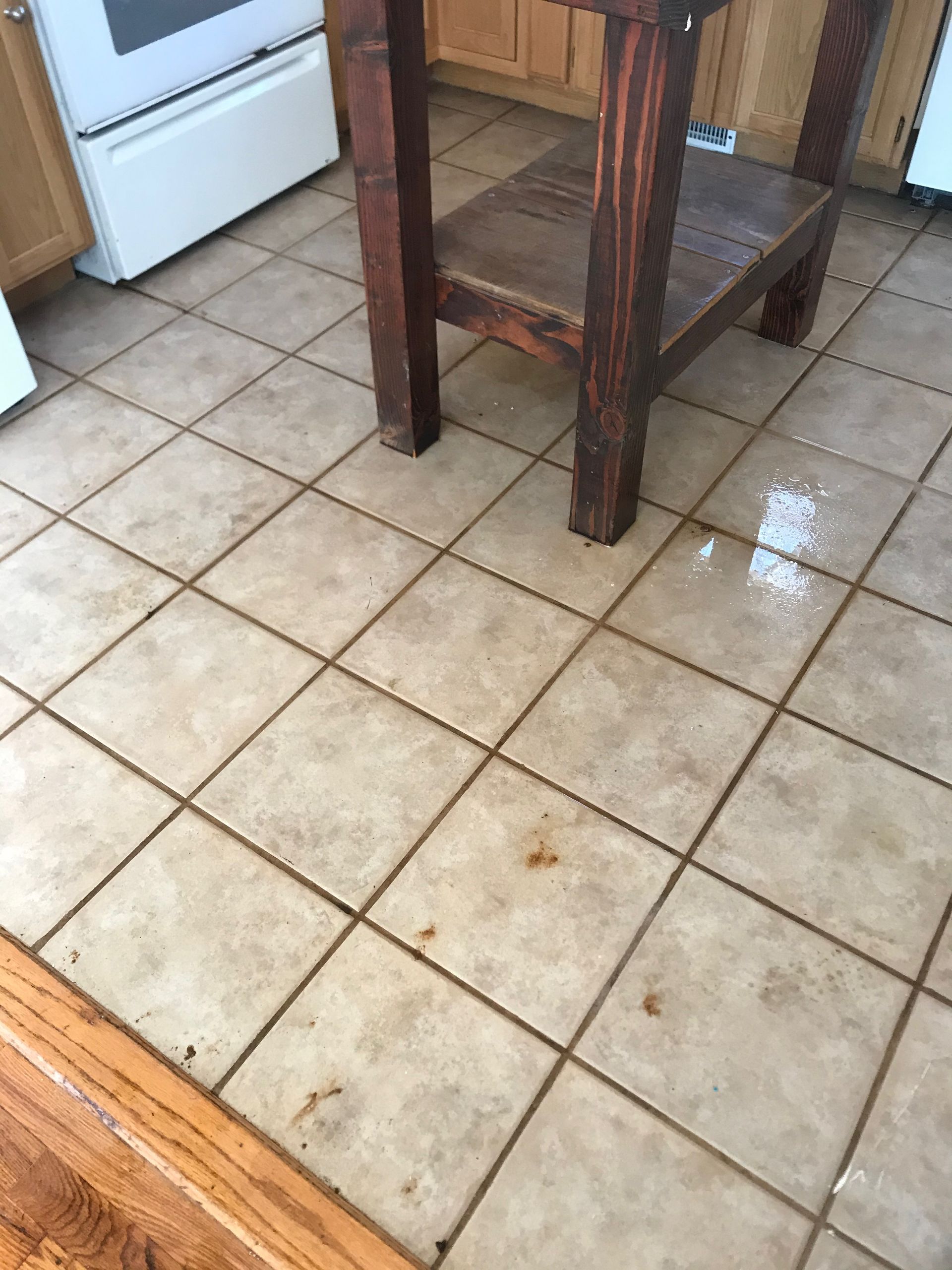 A wooden table is sitting on a tiled floor in a kitchen