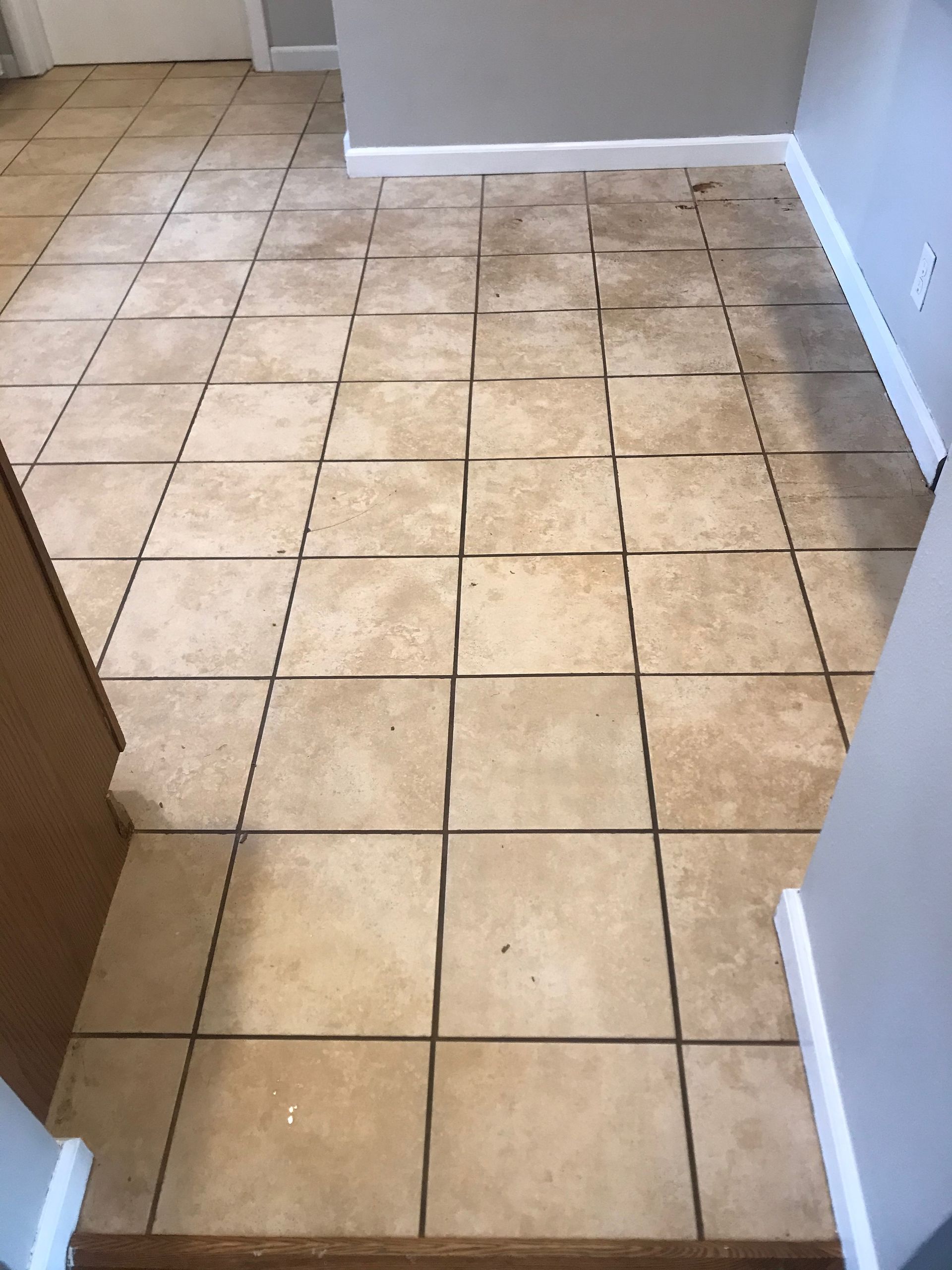 A dirty tile floor in a room with a doorway