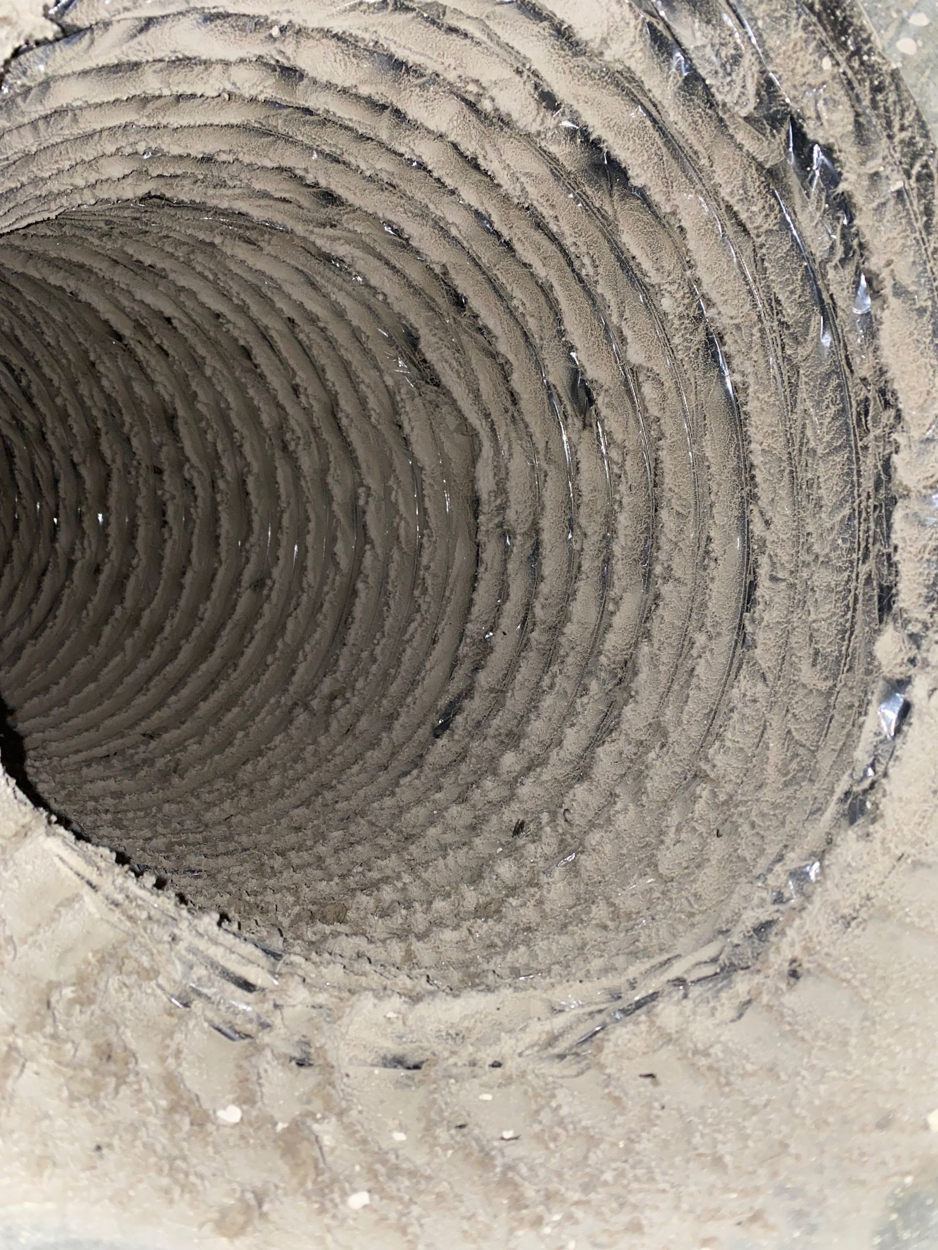 A close up of a dirty air duct with a hole in the middle.