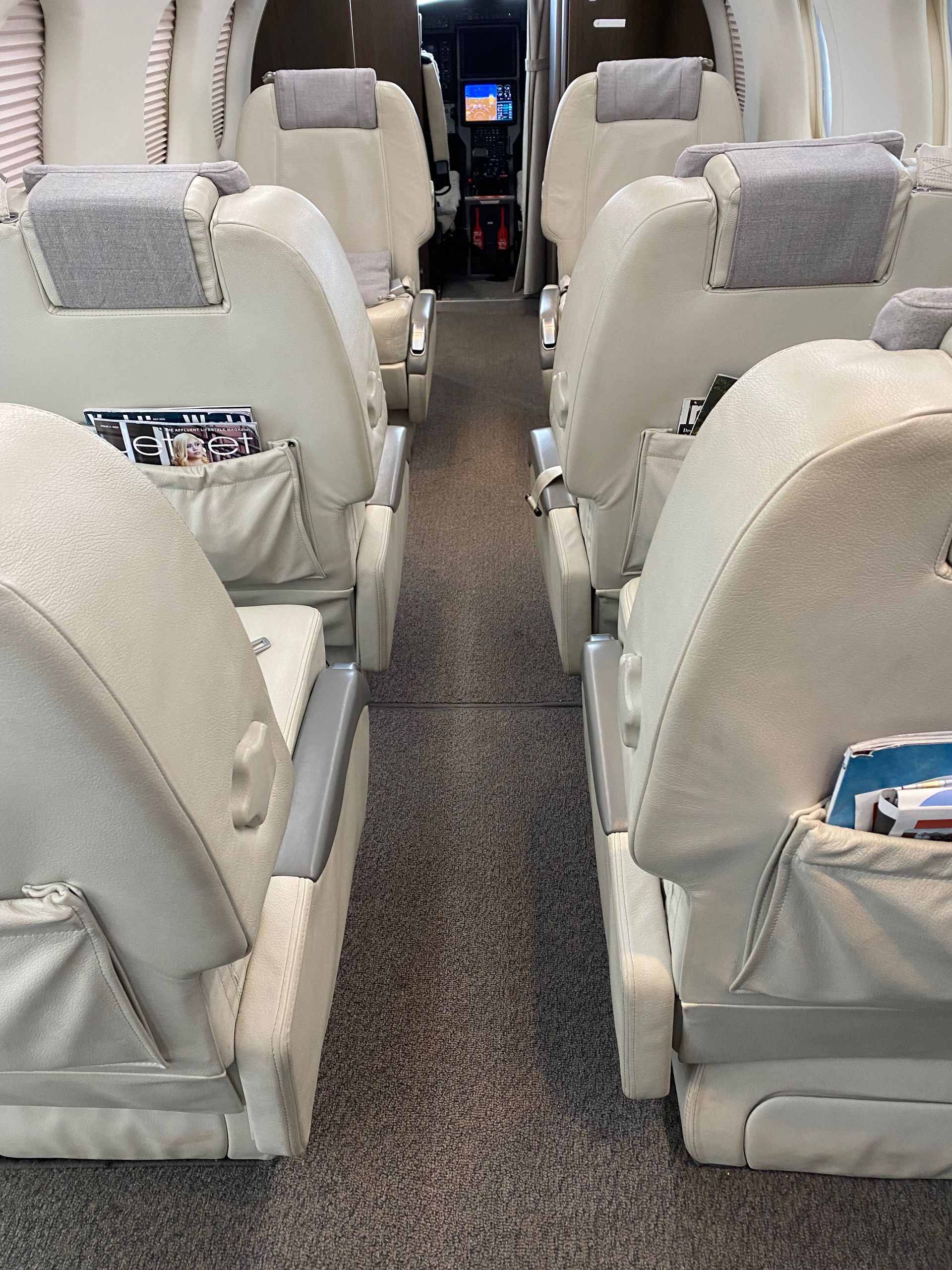 A row of seats on an airplane with a magazine in one of the pockets