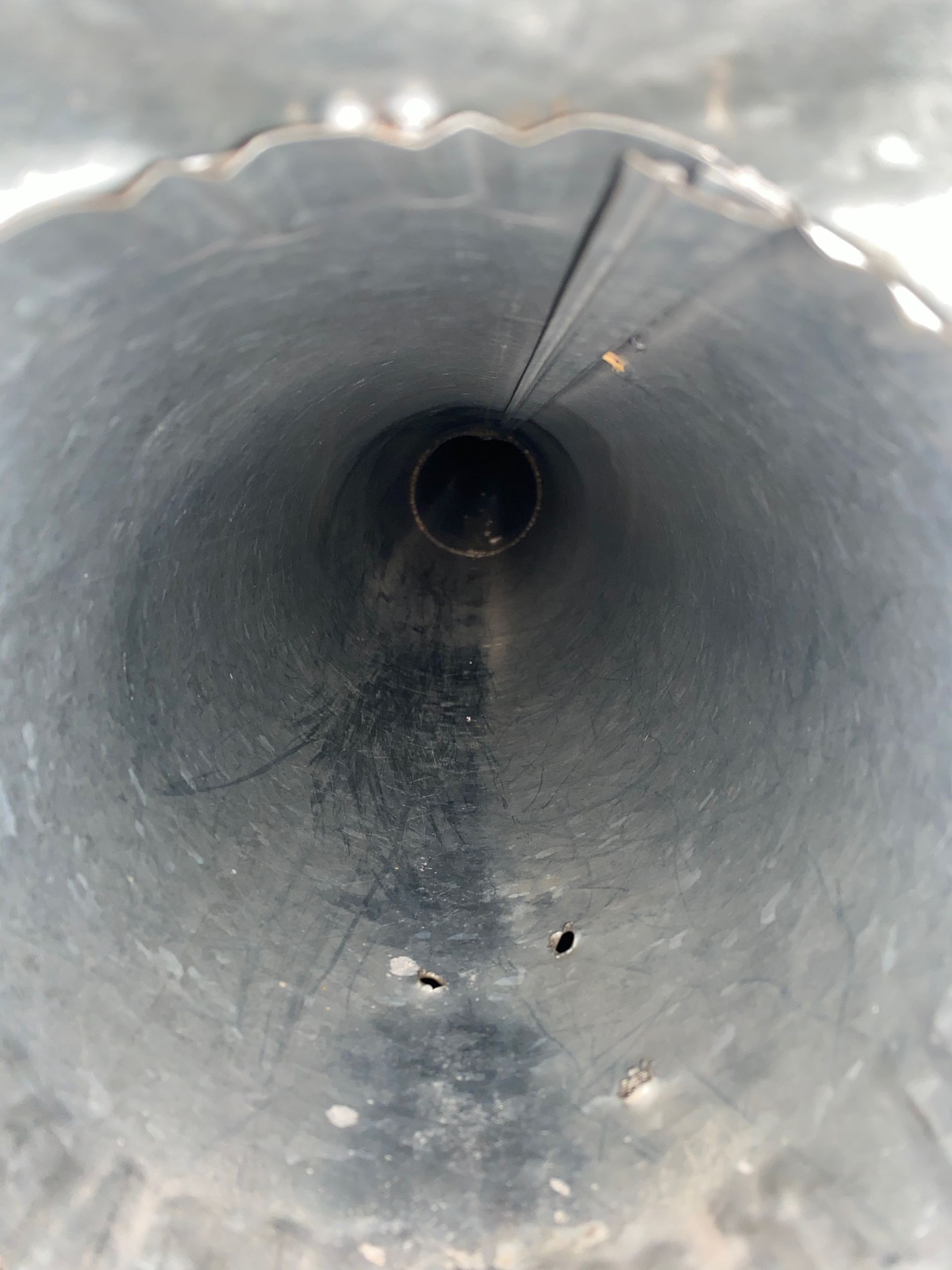The inside of a metal pipe with holes in it