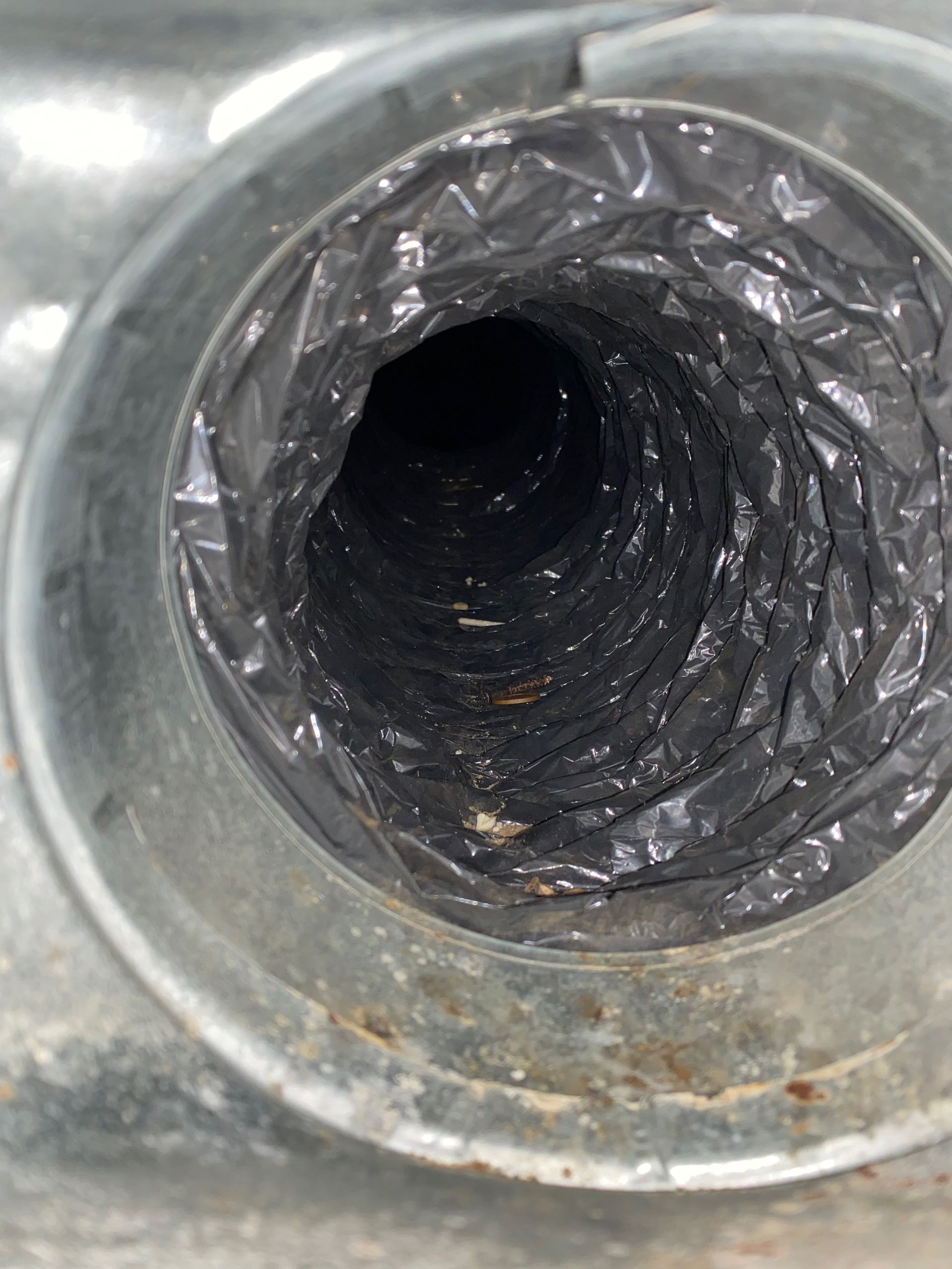 A close up of a dirty air duct with a plastic bag on it.