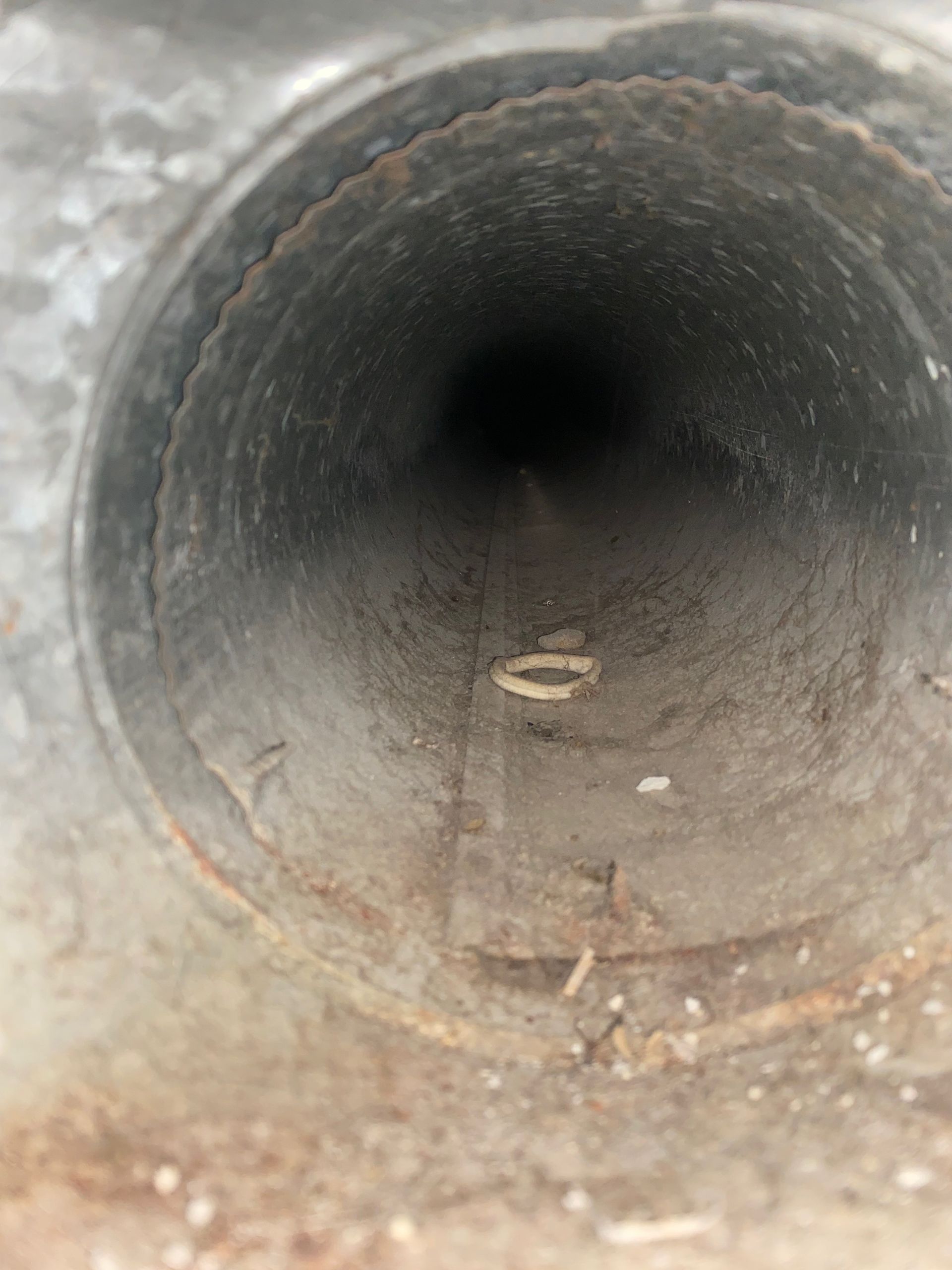 A close up of a dirty pipe with a hole in the middle.