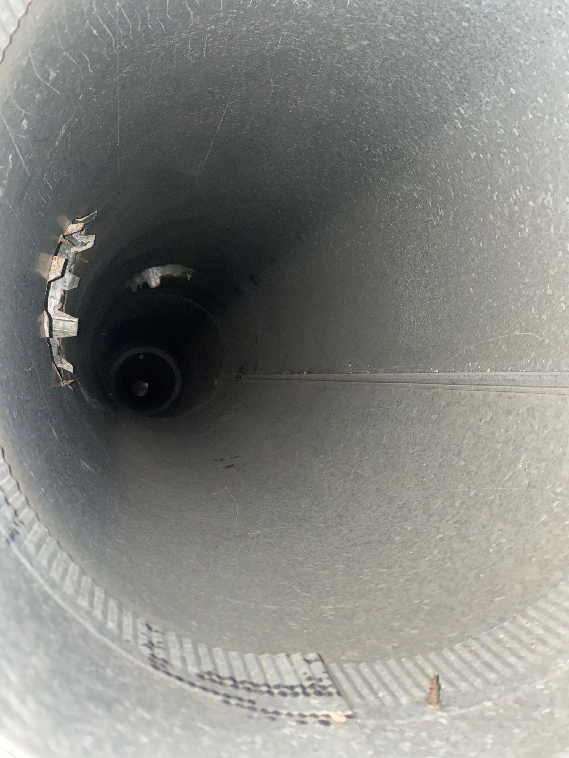 The inside of a metal pipe with a hole in it