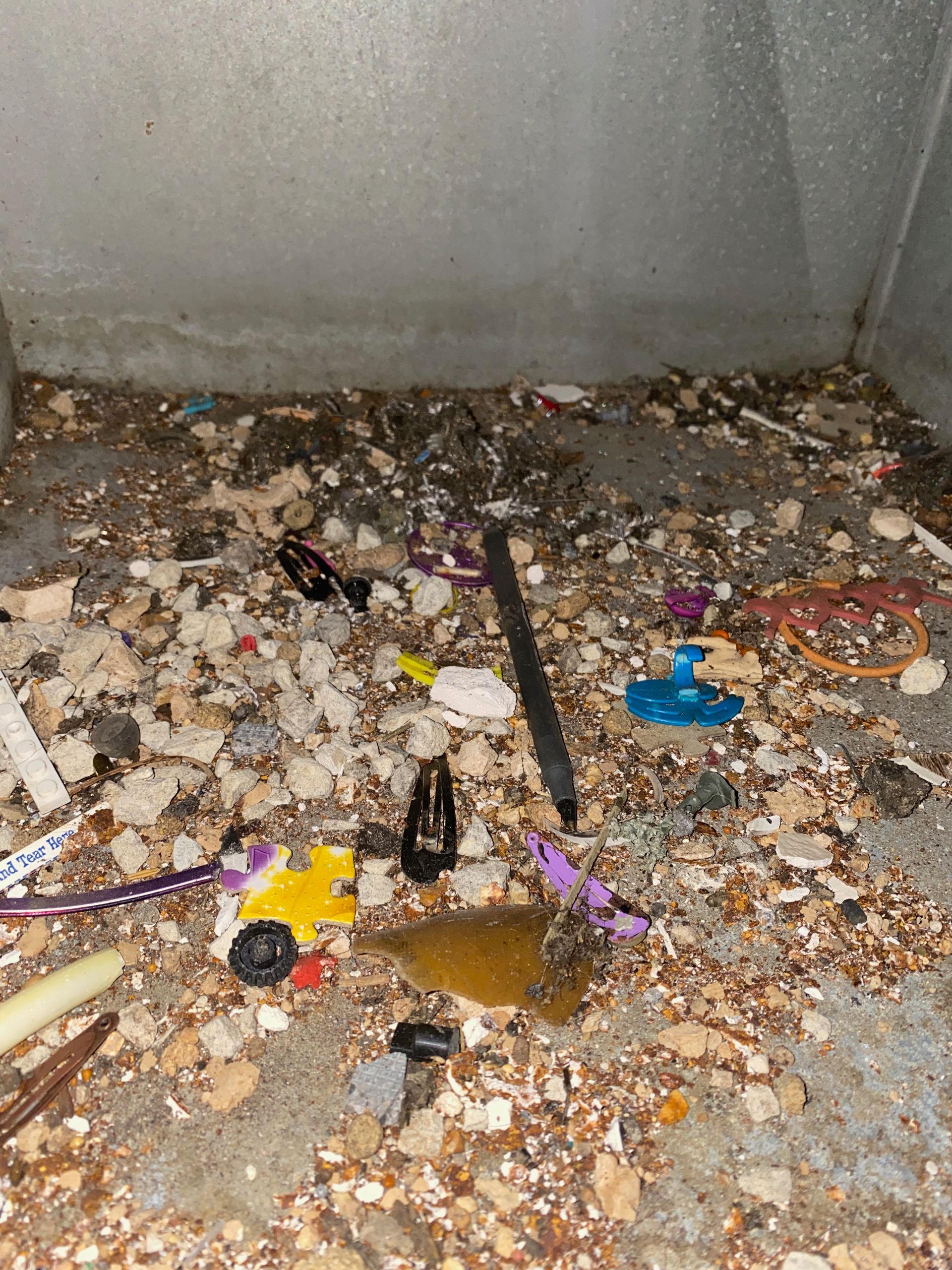 A pile of trash on the ground with a pen in the middle