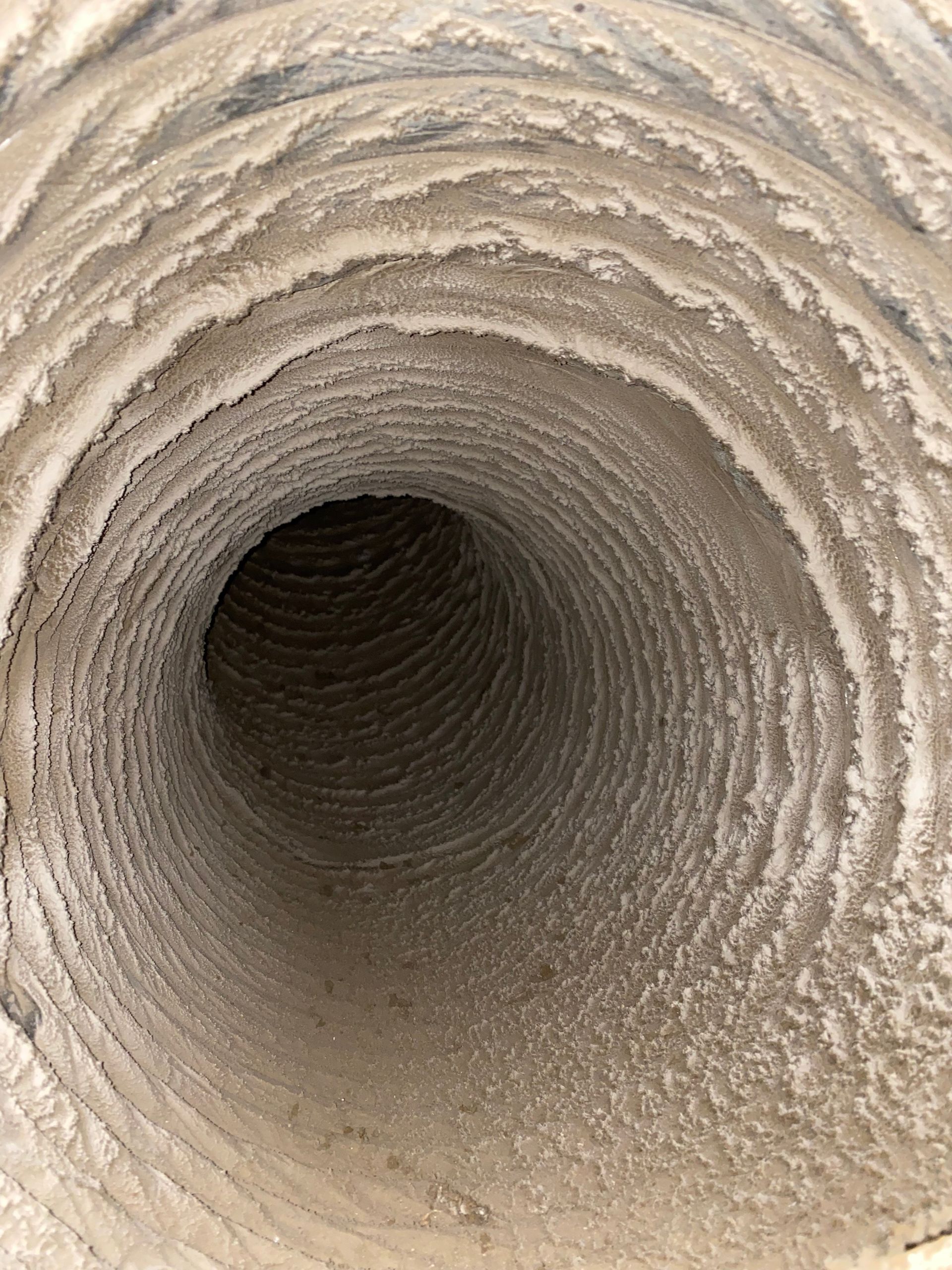 A close up of a dirty duct with a hole in the middle.