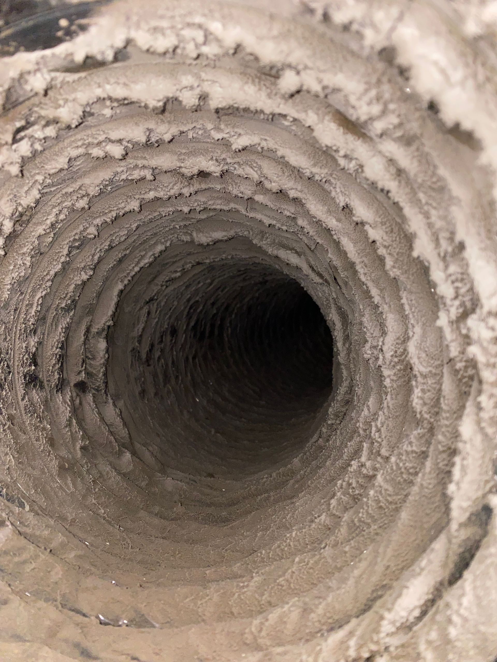 A close up of a dirty duct with a hole in the middle.