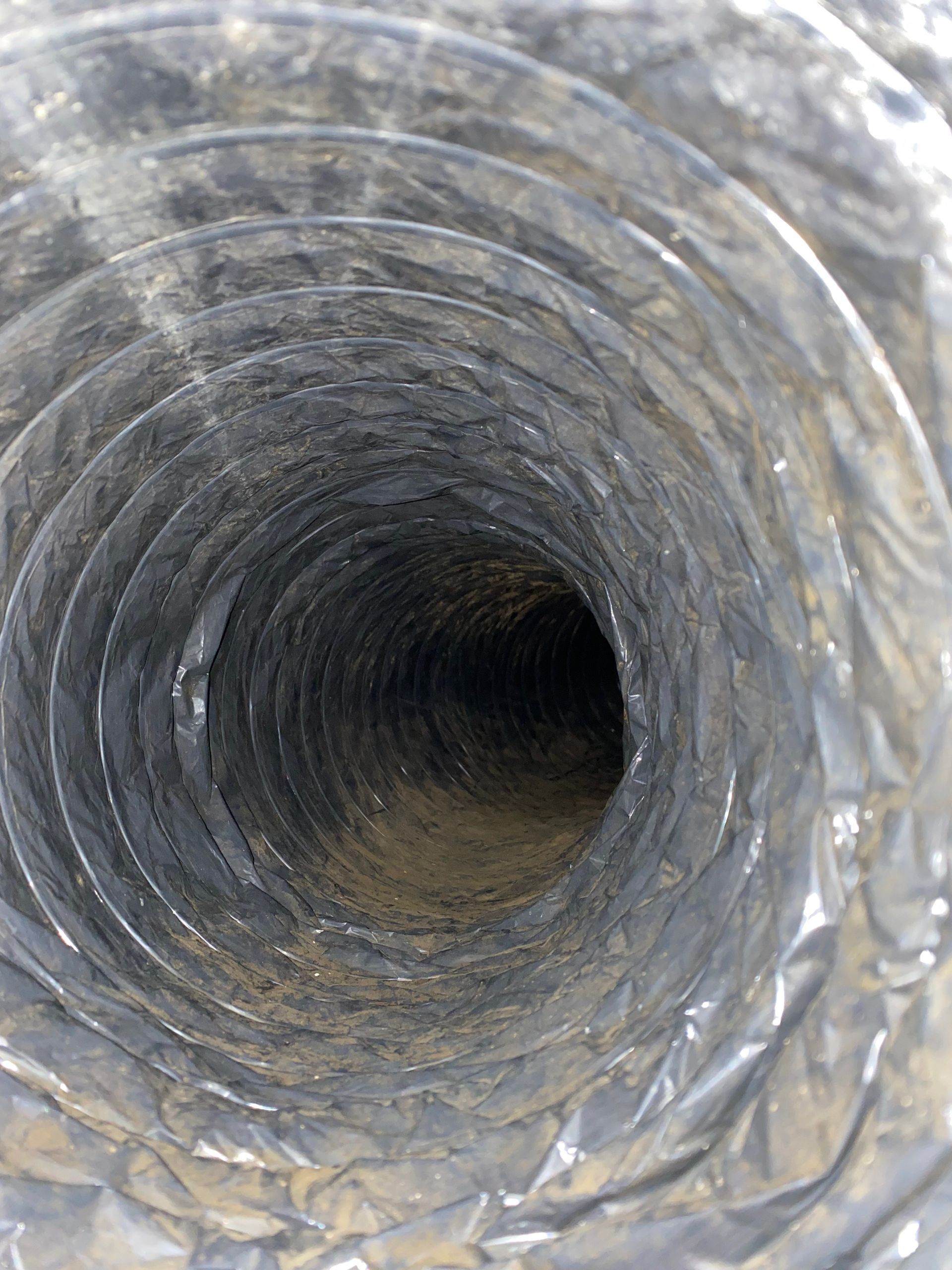 A close up of a dirty air duct with a hole in the middle.