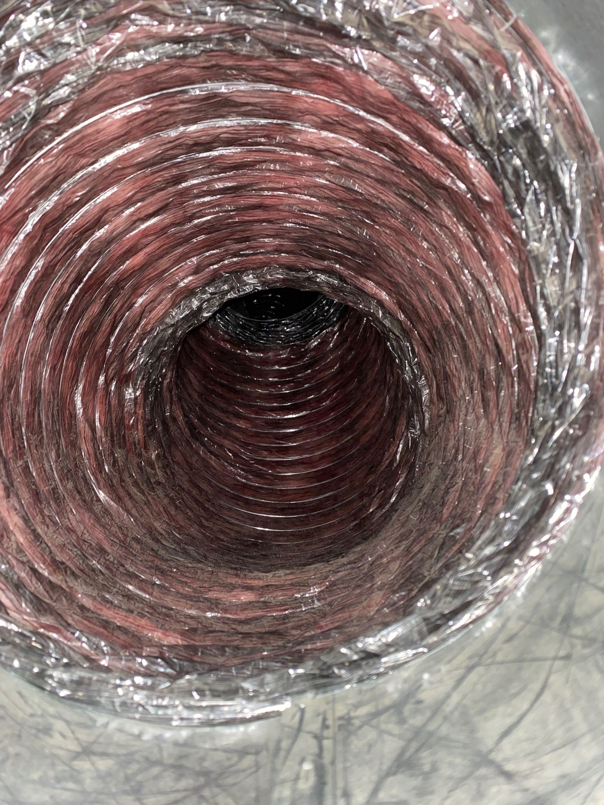 A close up of a red duct with a hole in the middle.