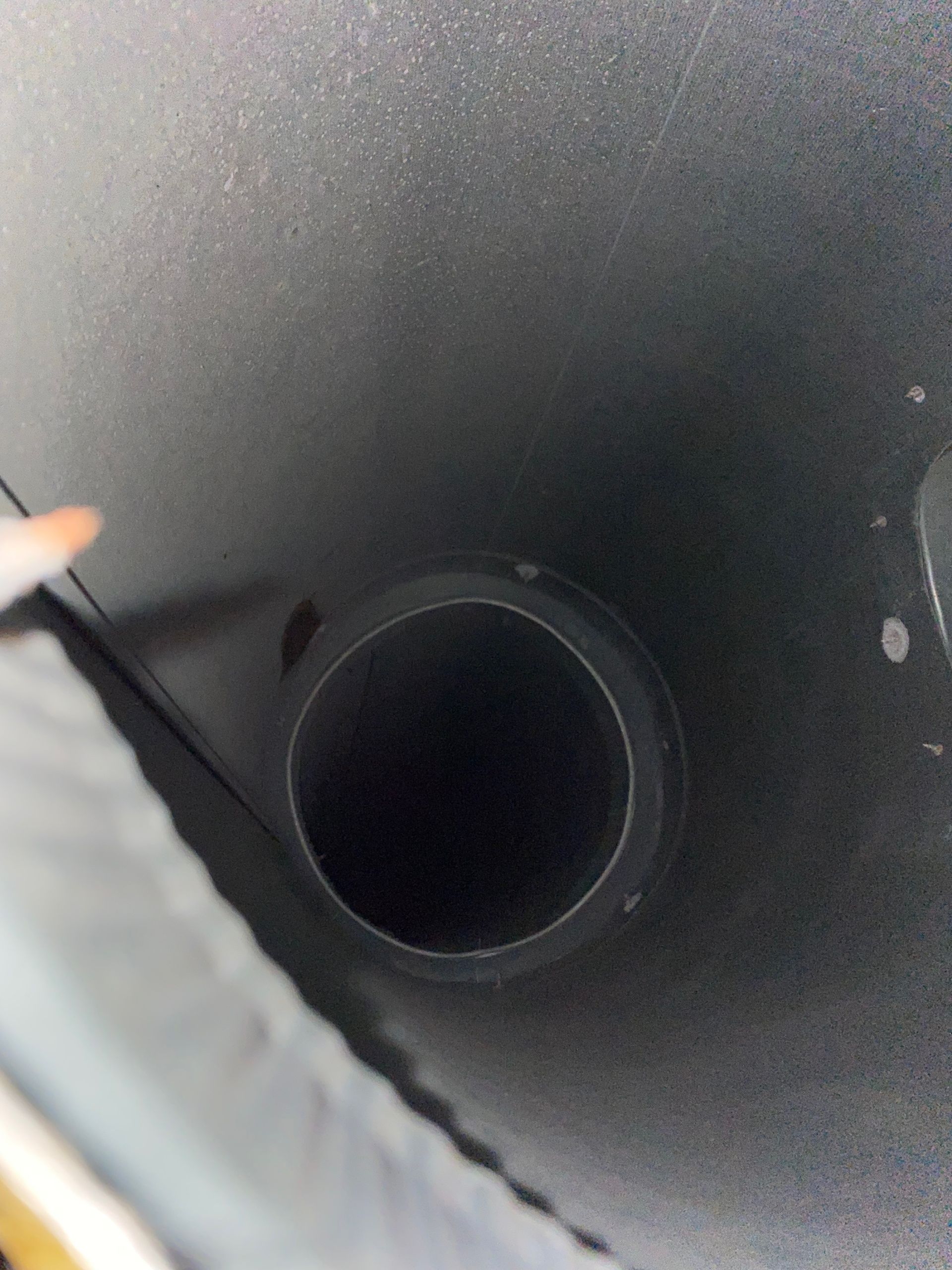 A person is pointing at a hole in a black object