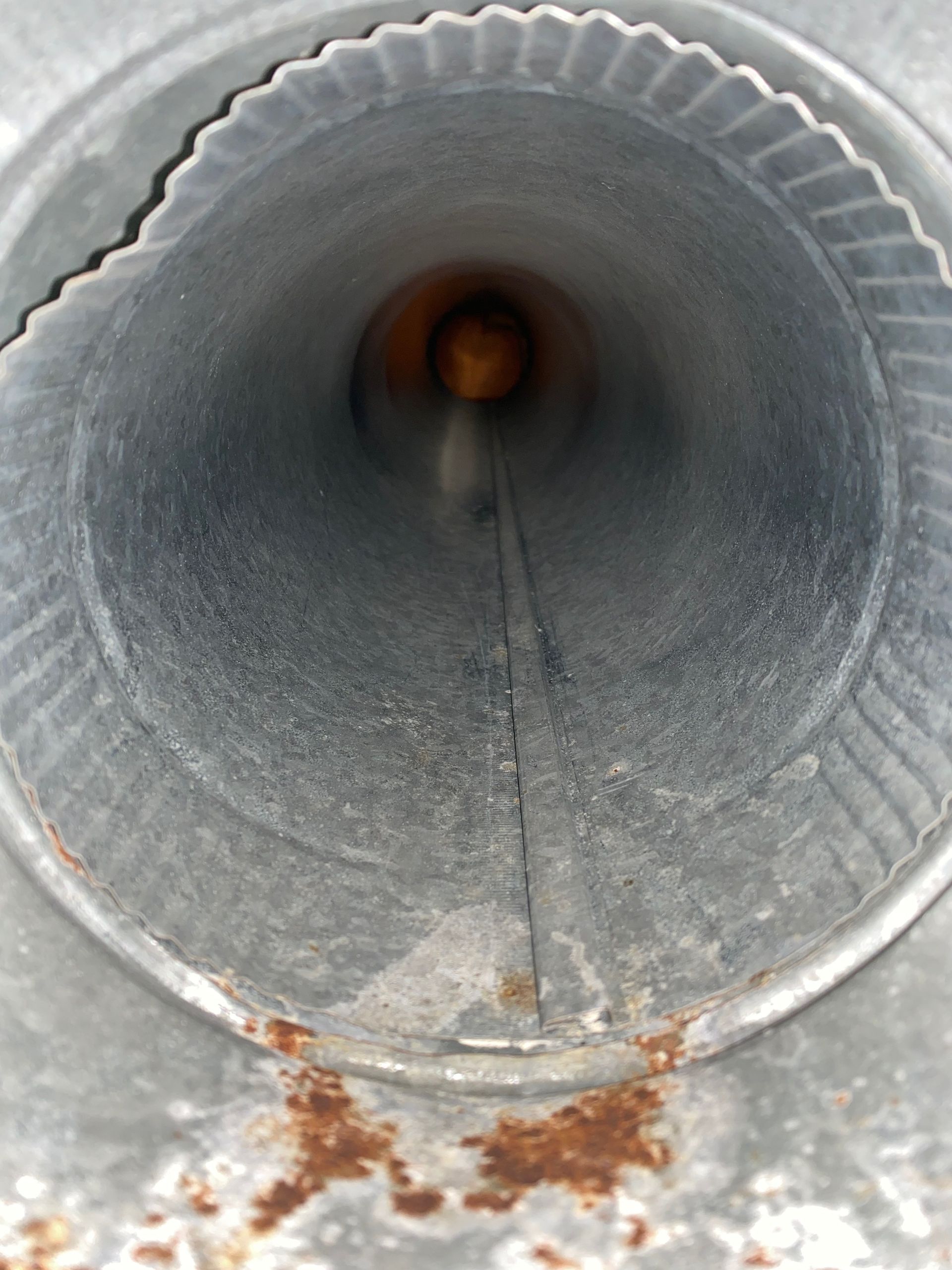 The inside of a metal pipe with rust on it