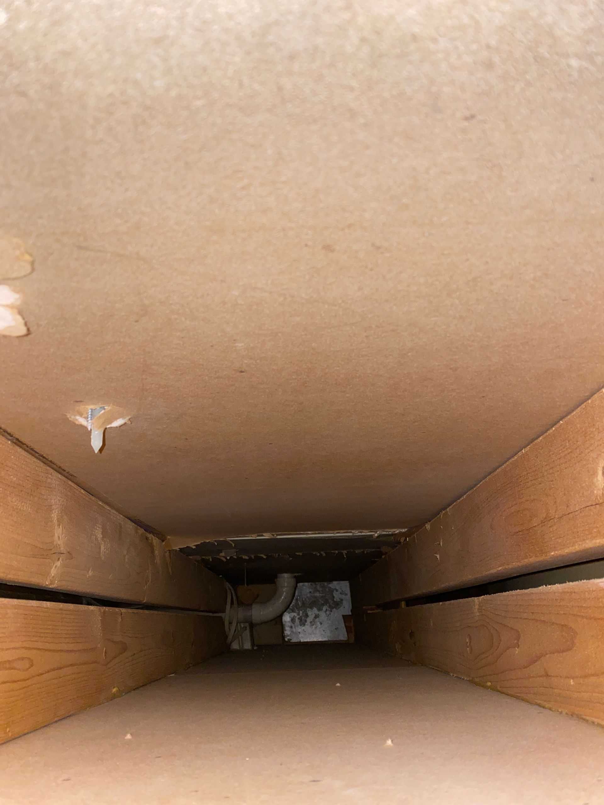 Looking down a wooden tunnel with a pipe in the middle