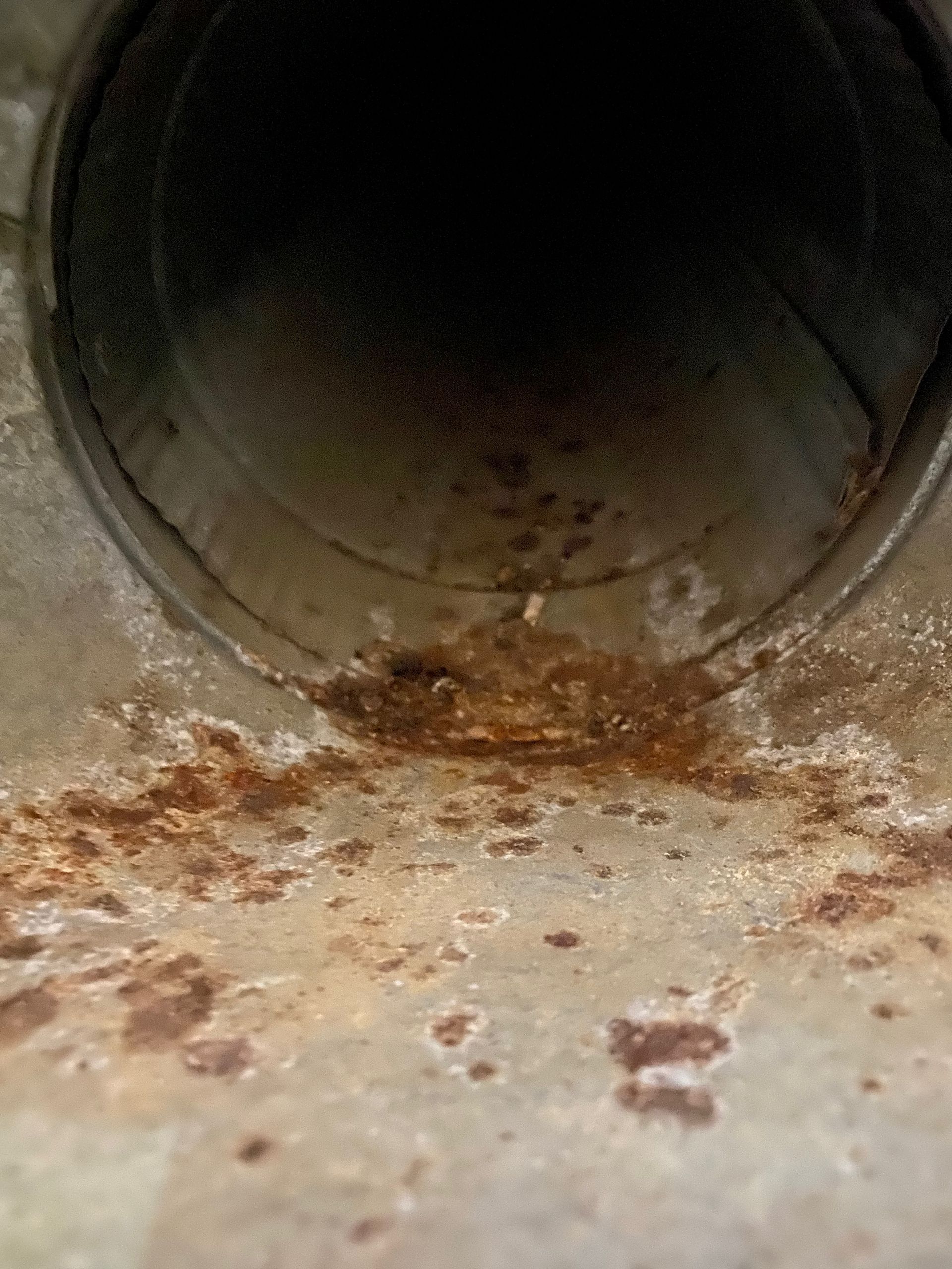 A close up of a rusty metal pipe on a concrete surface.