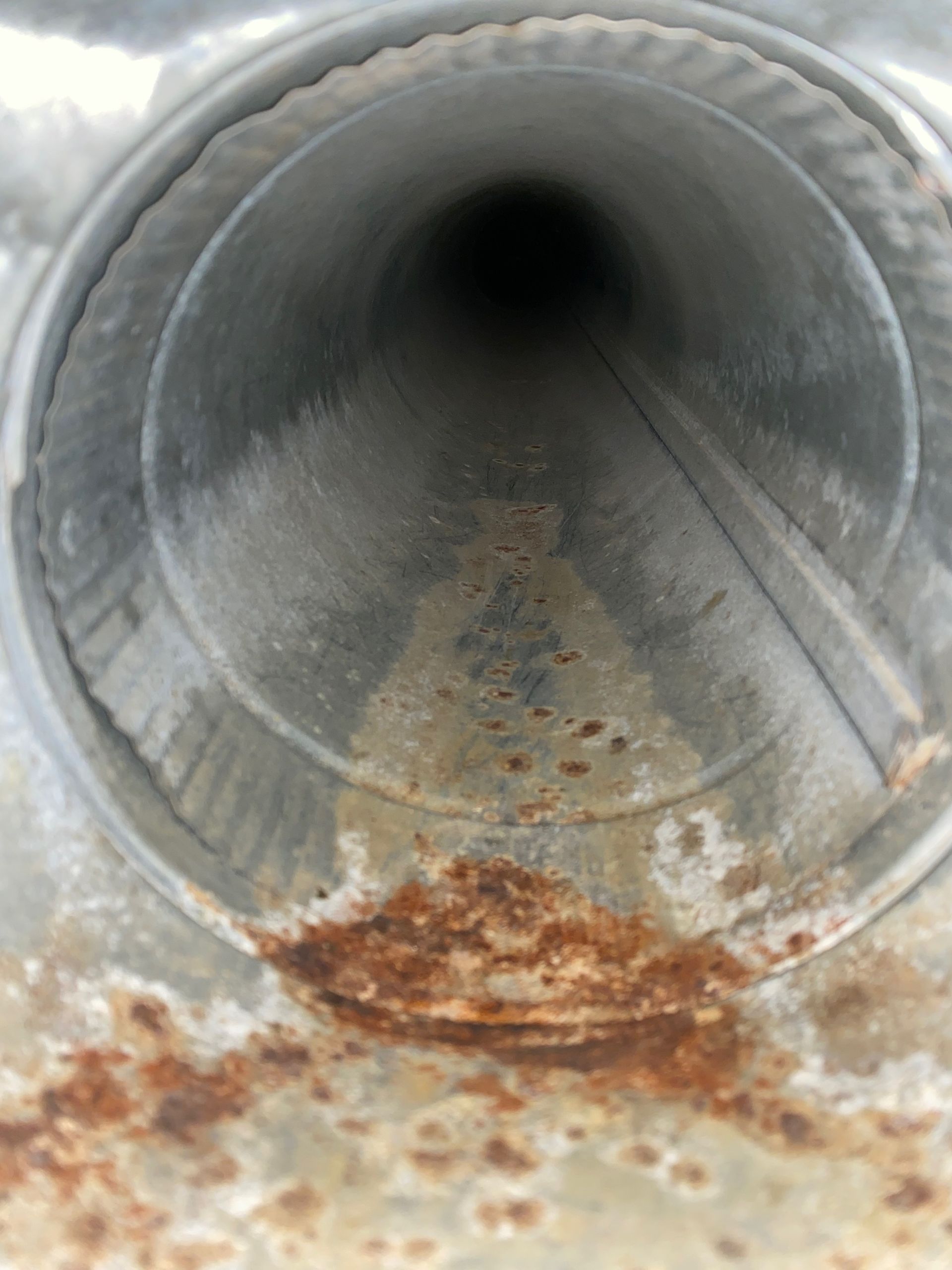 A rusty metal pipe with a hole in the middle