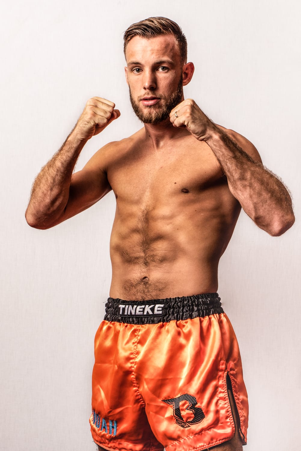 Een man zonder shirt draagt ​​een oranje boksbroek.