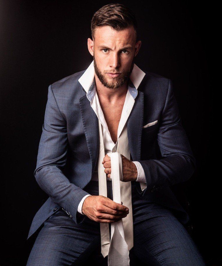 Een man in pak zit en knoopt zijn stropdas vast.