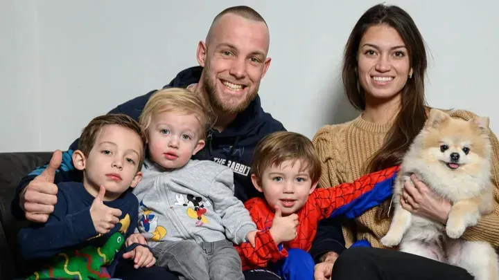 Een gezin poseert voor een foto terwijl ze op een bank zitten.