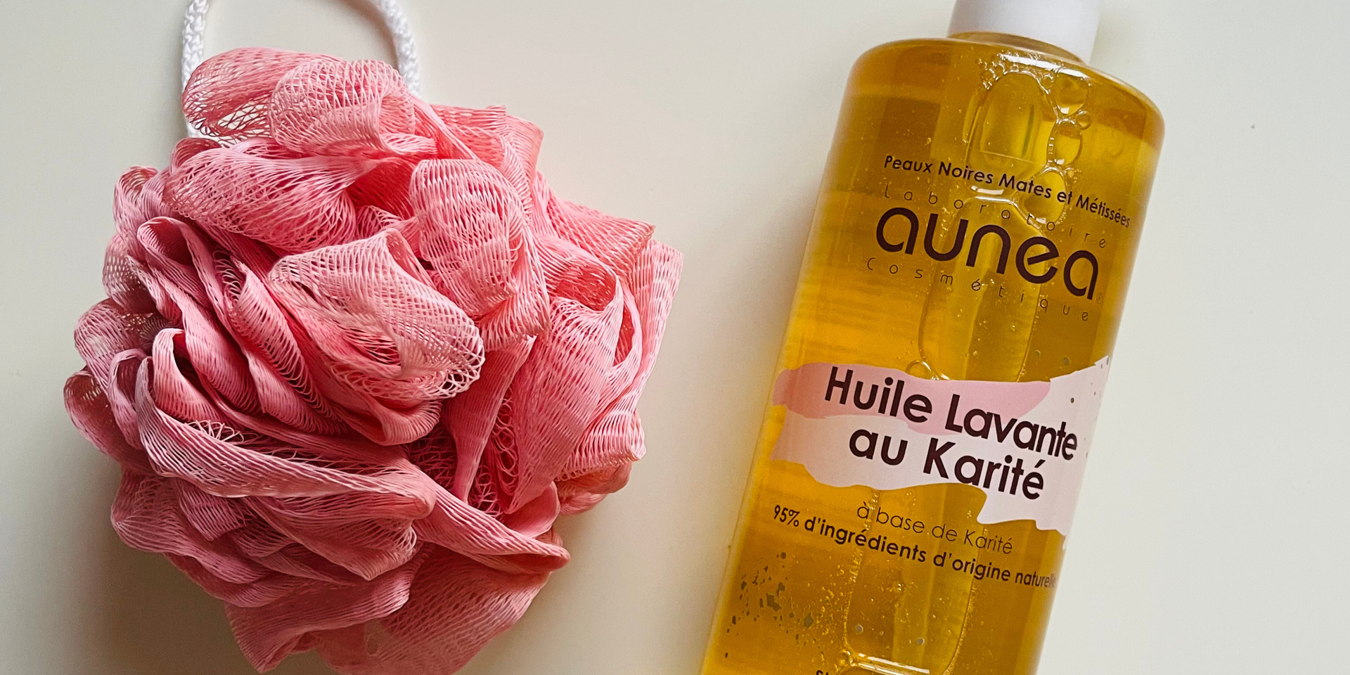 Fleur de bain rose et flacon d'huile « aunea » avec inscription en français.