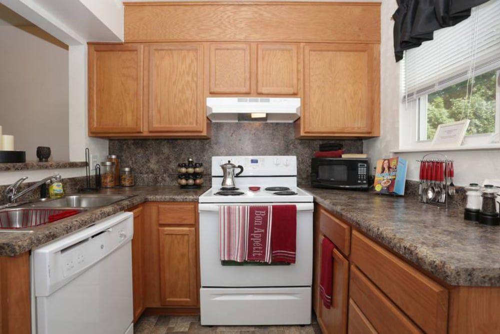 A kitchen with a stove , sink , and dishwasher at Old Mill Townhomes in Lynchburg, VA.