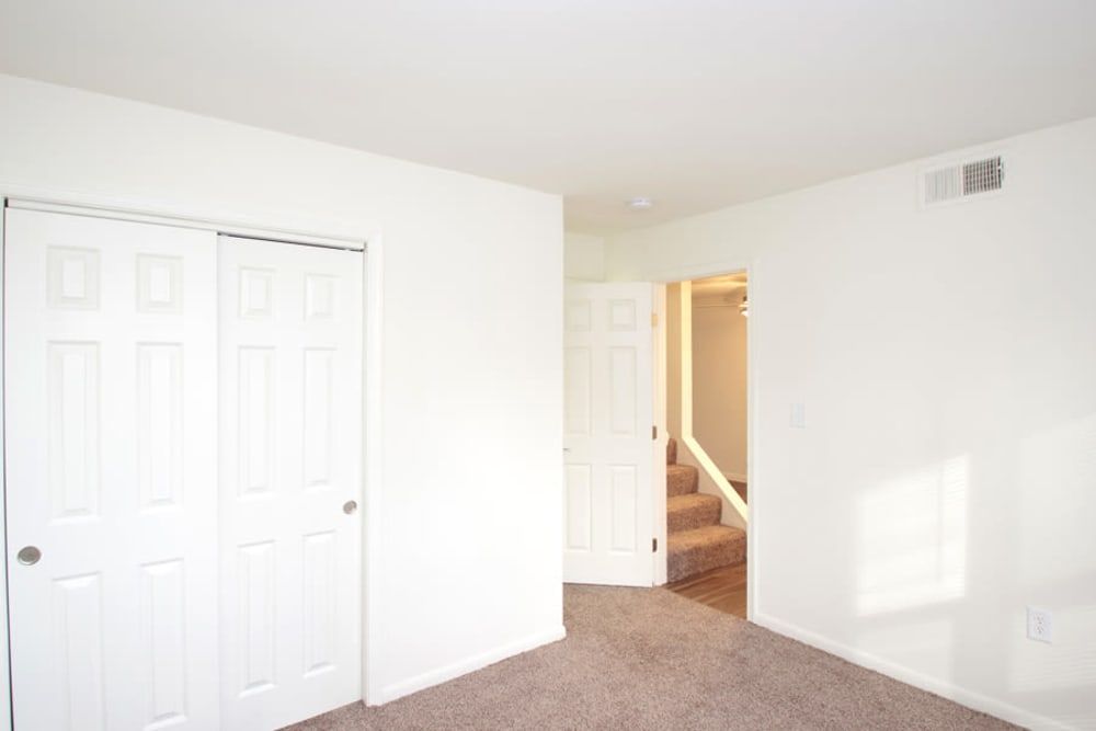 An empty bedroom with a staircase and a closet at Old Mill Townhomes in Lynchburg, VA.