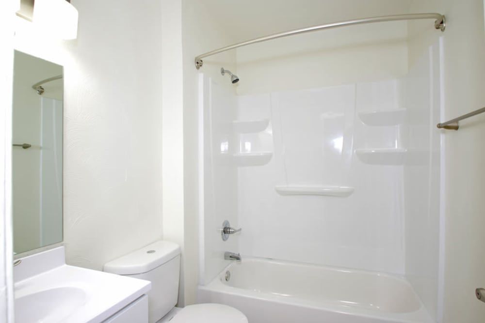 A bathroom with a toilet , sink , shower and mirror at Old Mill Townhomes in Lynchburg, VA.