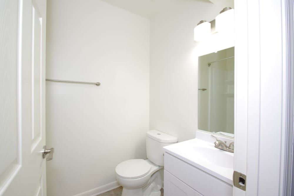 A bathroom with a toilet , sink and mirror at Old Mill Townhomes in Lynchburg, VA.