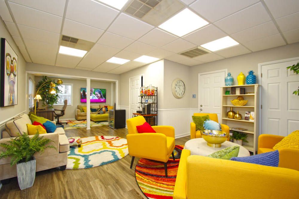 A living room filled with colorful furniture and a clock on the wall at Old Mill Townhomes in Lynchburg, VA.