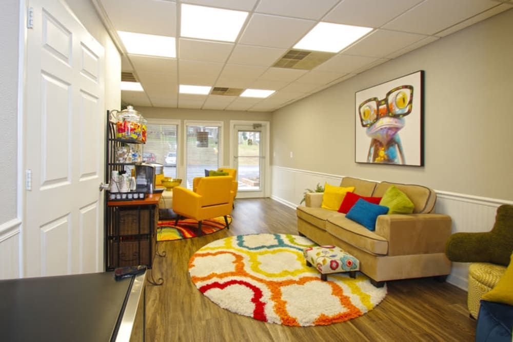 A living room with a couch , chairs , a rug and a painting on the wall at Old Mill Townhomes in Lynchburg, VA.