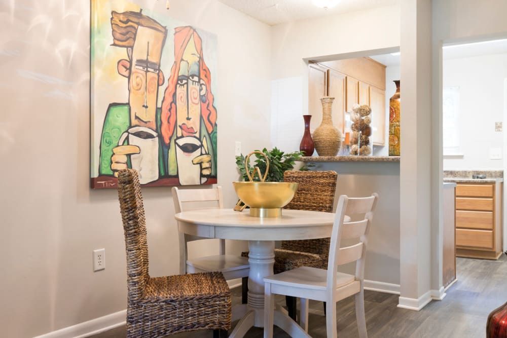 A dining room with a table and chairs and a painting on the wall at Old Mill Townhomes in Lynchburg, VA.