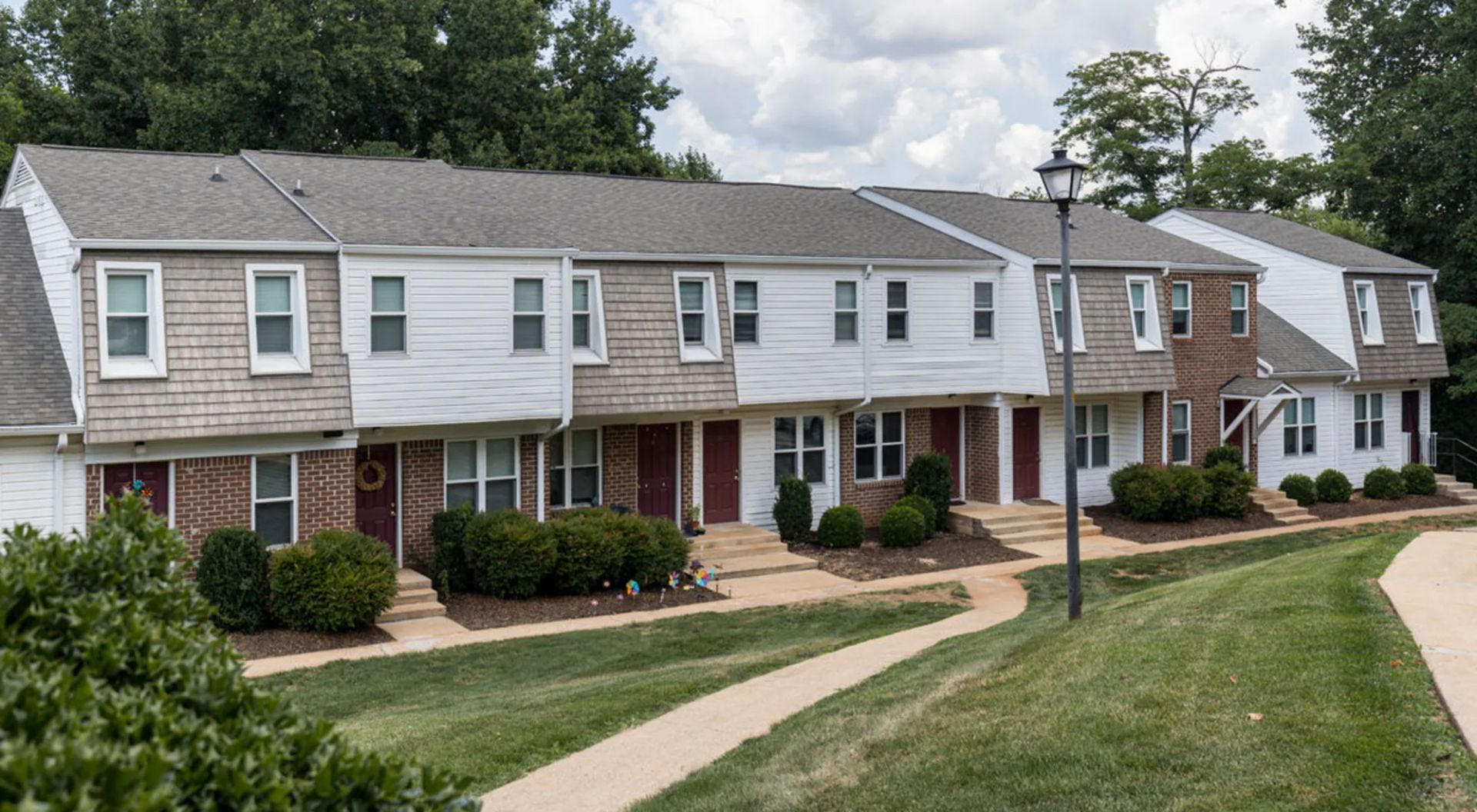 A row of apartment buildings with a walkway between them at Old Mill Townhomes in Lynchburg, VA.