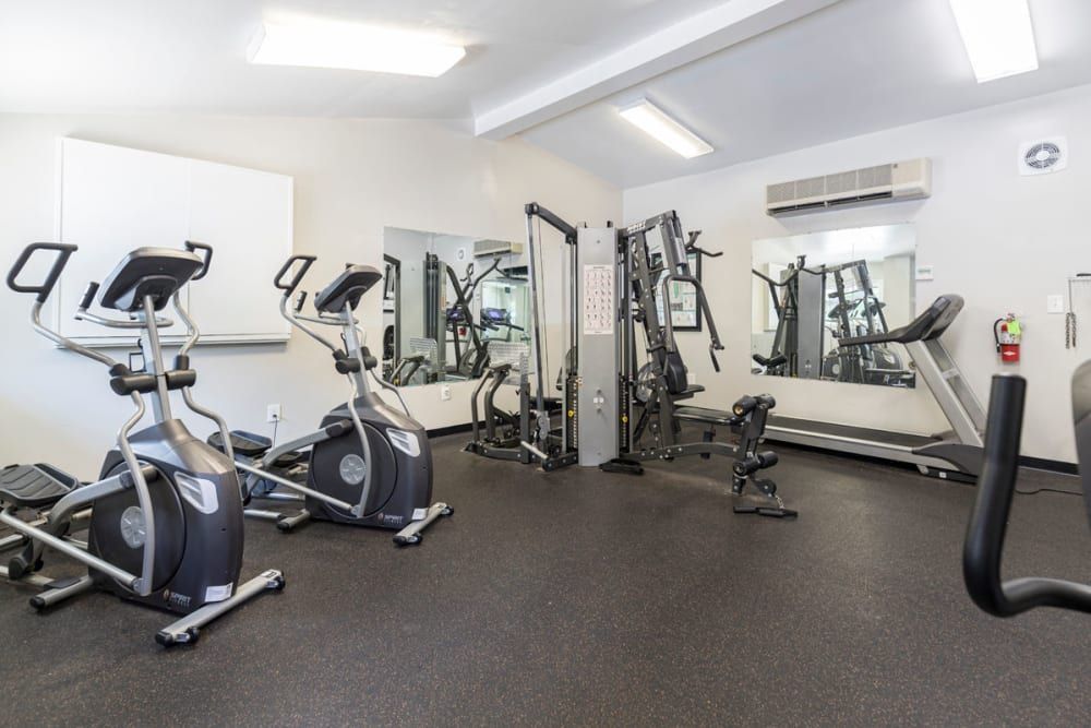 A gym with a lot of exercise equipment and a large mirror at Old Mill Townhomes in Lynchburg, VA.