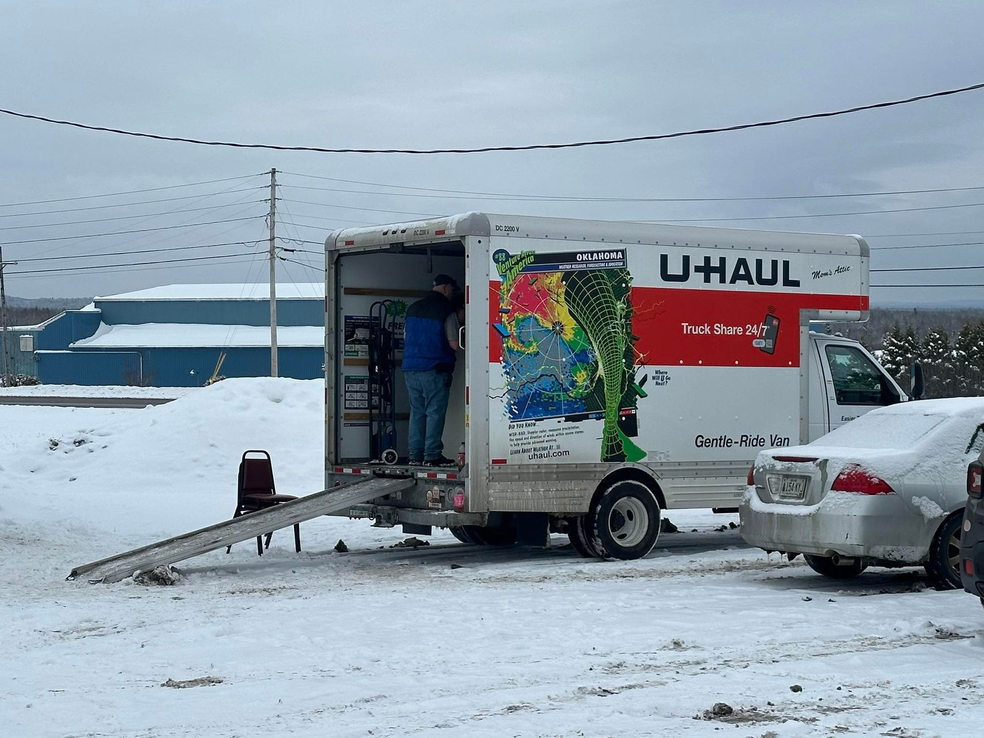 Eight people in matching red t-shirts stand and sit in front of a wooden play structure outdoors on a sunny day.