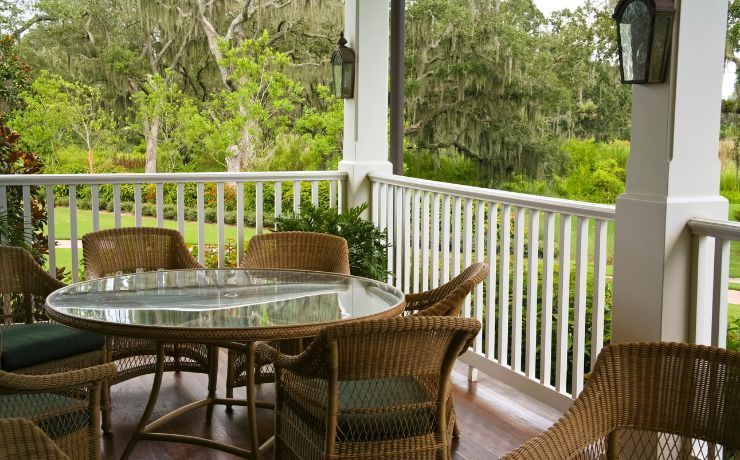 Traditional porch overlooking a lush Salinas landscape, with comfortable wicker furniture on a polished wooden floor and white balustrade railing.