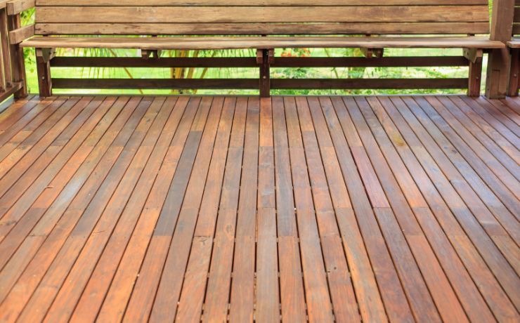 A spacious, warm-toned wooden deck in Salinas featuring a long bench, ready for outdoor gatherings in a serene, natural setting.