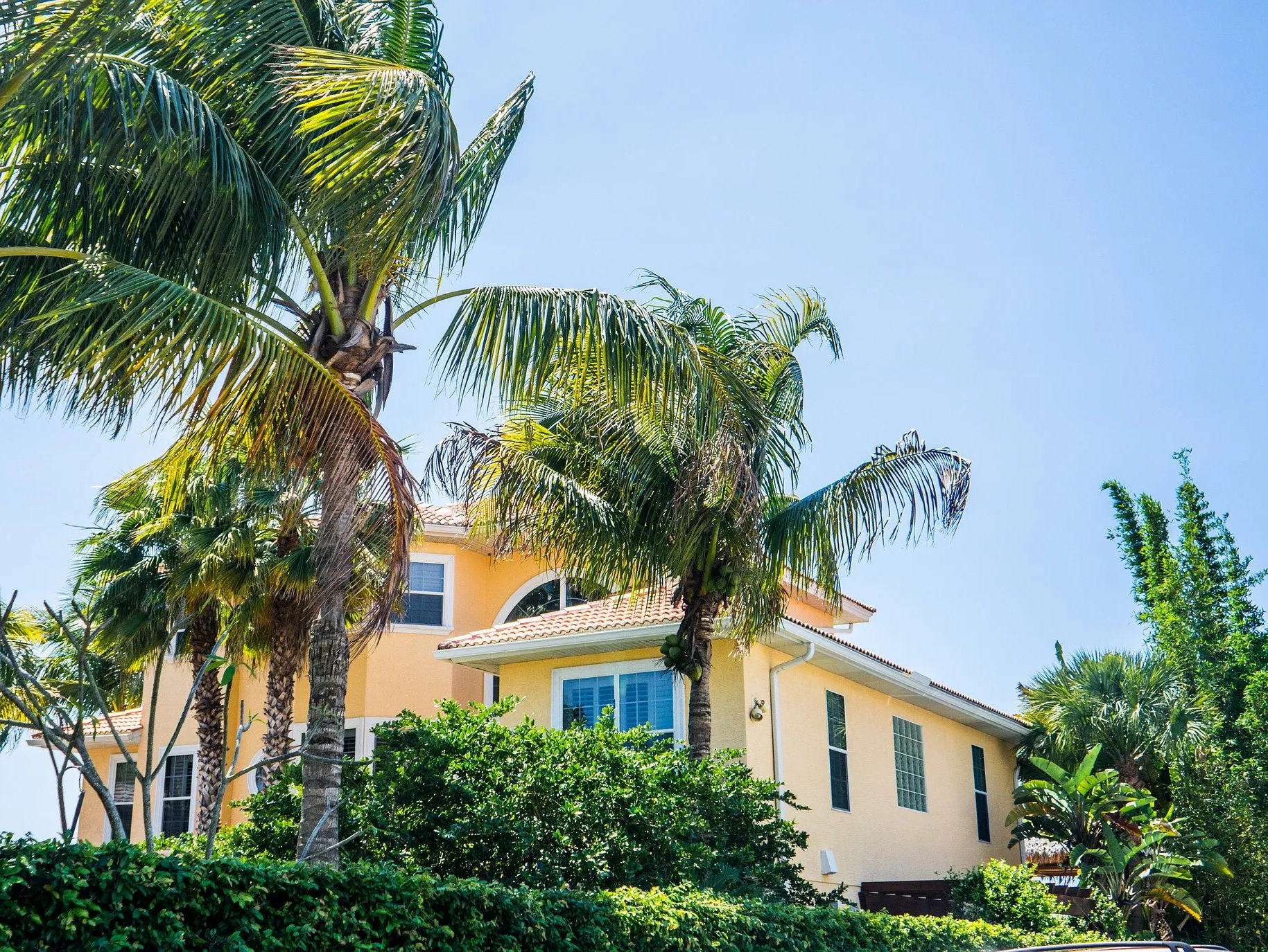 A large yellow house with palm trees in front of it.