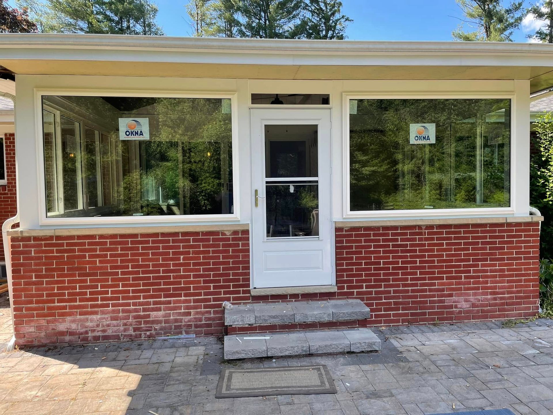 Brick exterior with white door, three windows, and concrete steps.