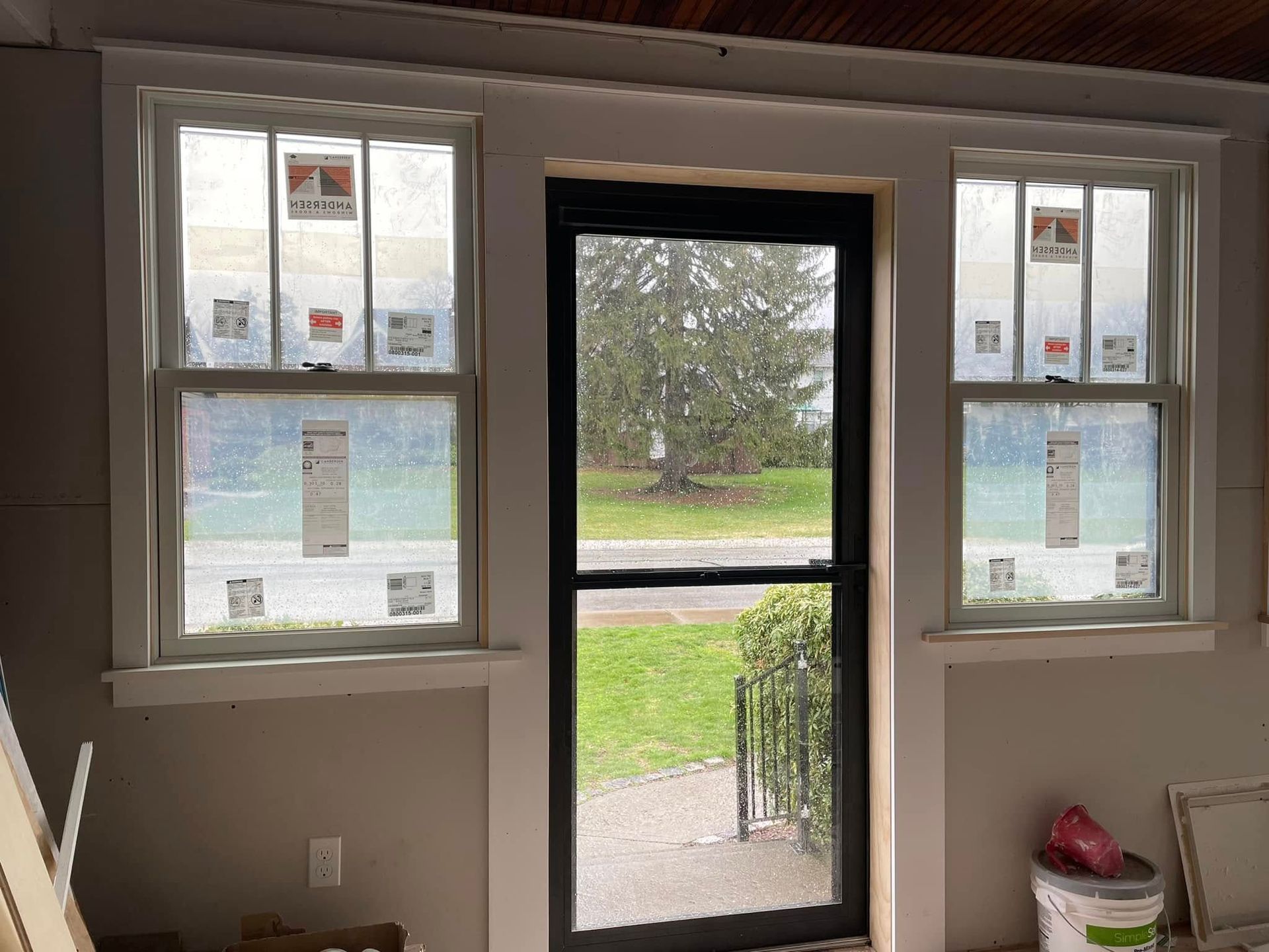 Exterior view: a black door with two flanking windows, all framed in white.