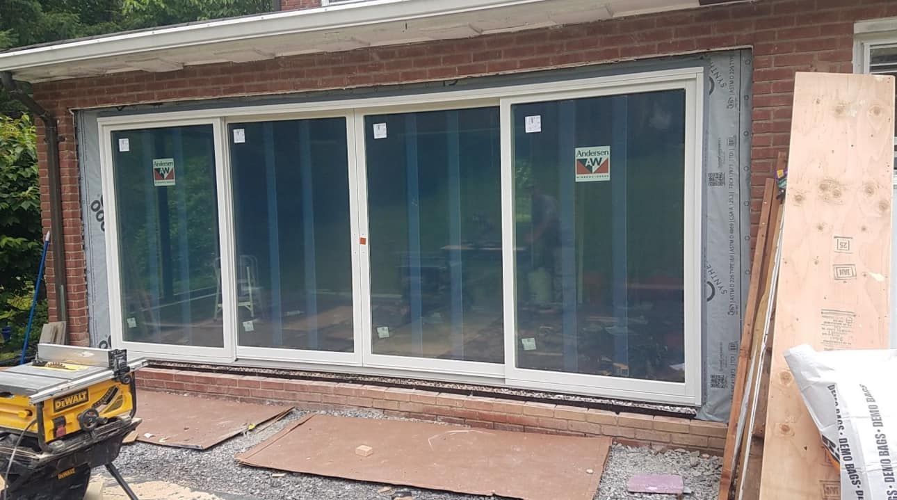 Large white-framed sliding glass doors installed in a brick building under construction.