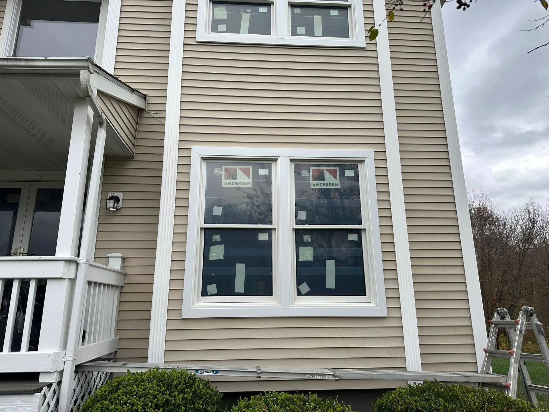 Beige house exterior with wavy siding, new windows, and white trim.