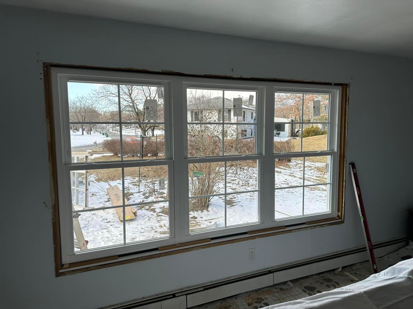 A triple-pane window installed in a wall, overlooking a snowy outdoor scene.