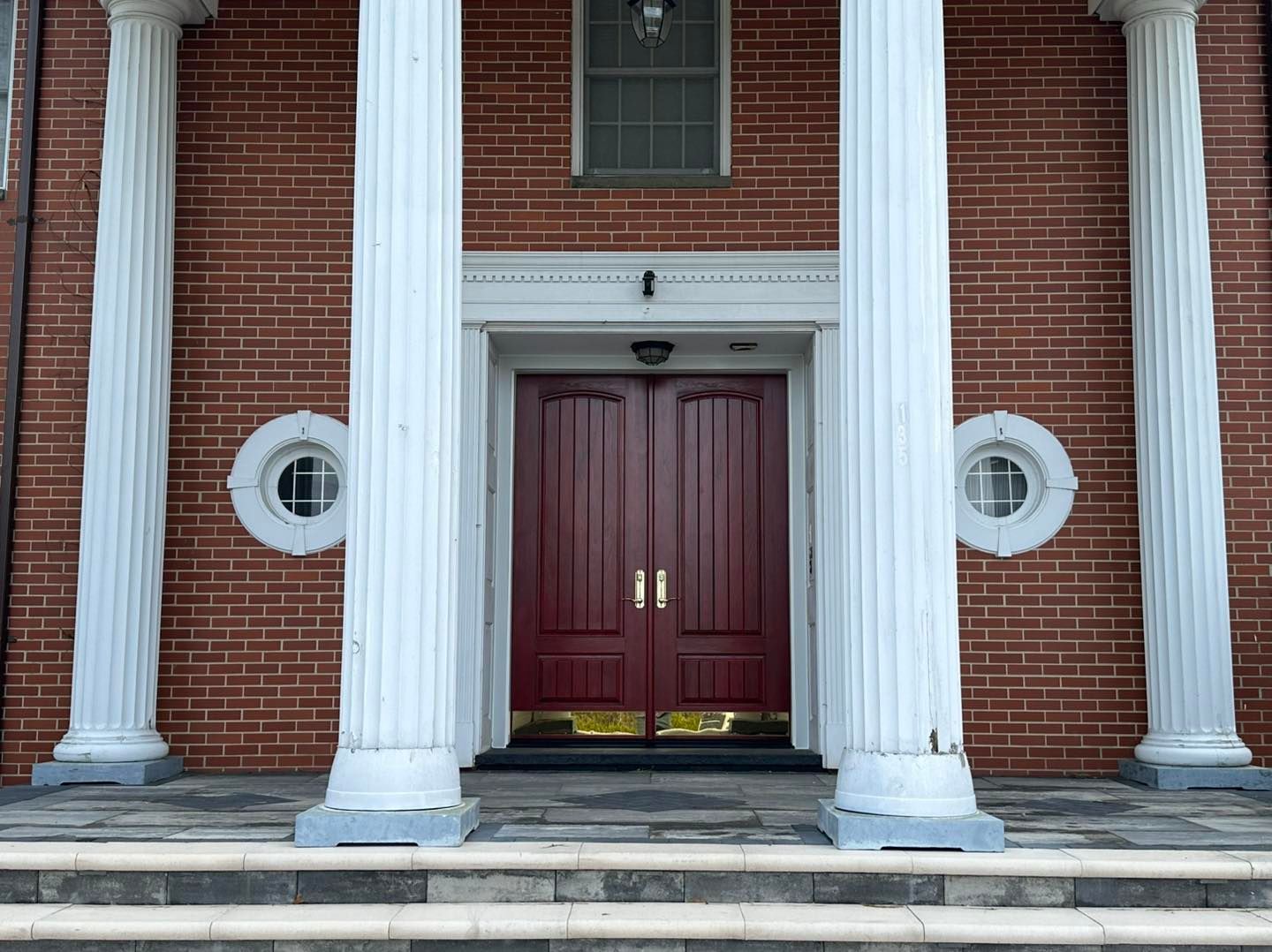Red brick building with white columns and double maroon doors.