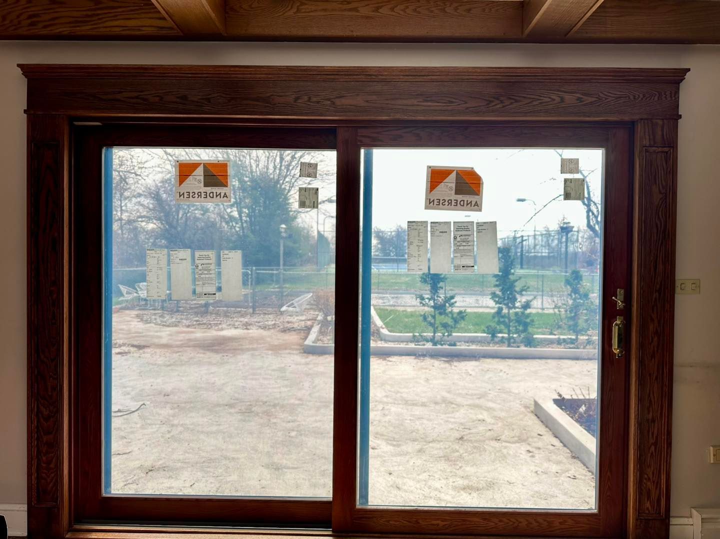 Sliding glass door with dark wood trim; construction site visible outside.