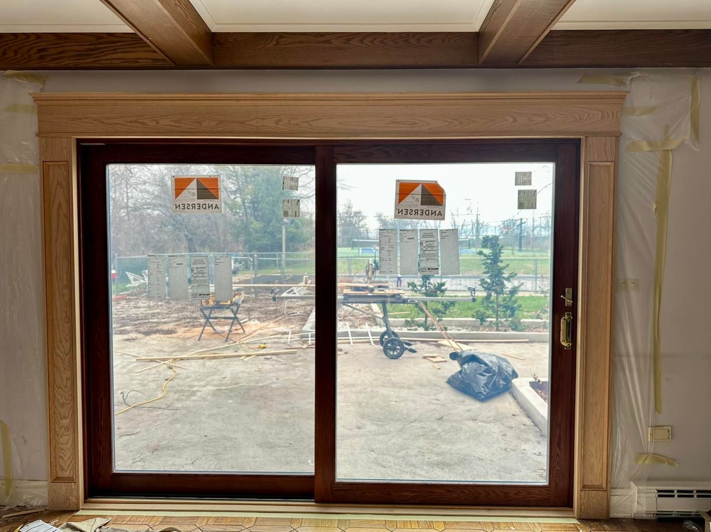 Sliding glass door with wooden trim, looking out to a construction site on a cloudy day.