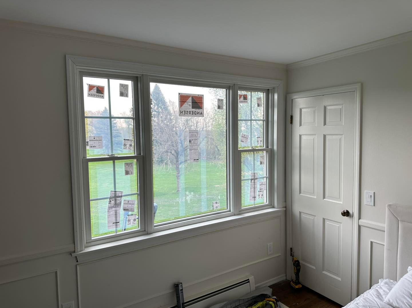 Room interior with a large window, white trim, and a closed white door.