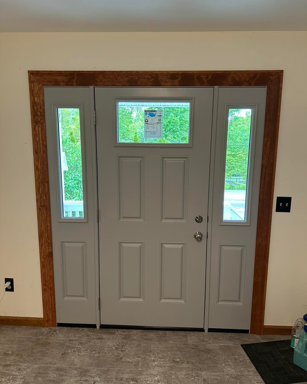 Gray door with sidelights, wooden trim, and a small transom window.