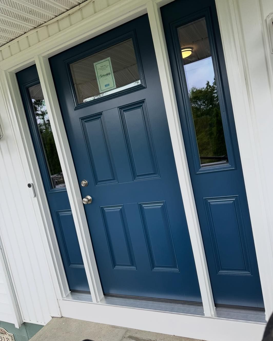 Blue front door with sidelights, white trim, and a small window above.