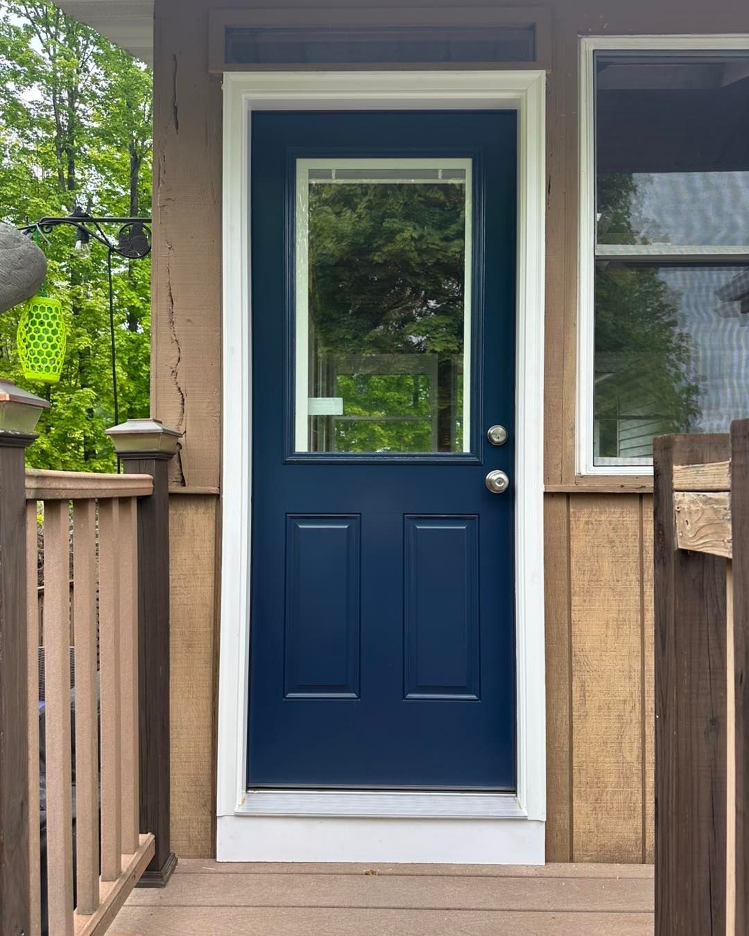 Blue door with glass panel, white trim, on a porch.