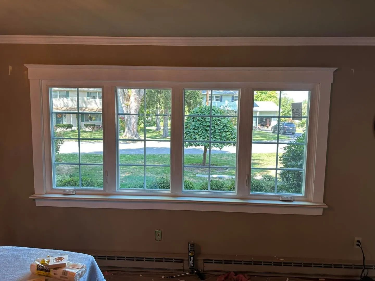 Four-pane window with white trim, view of a street and a tree, set in a room with tan walls.